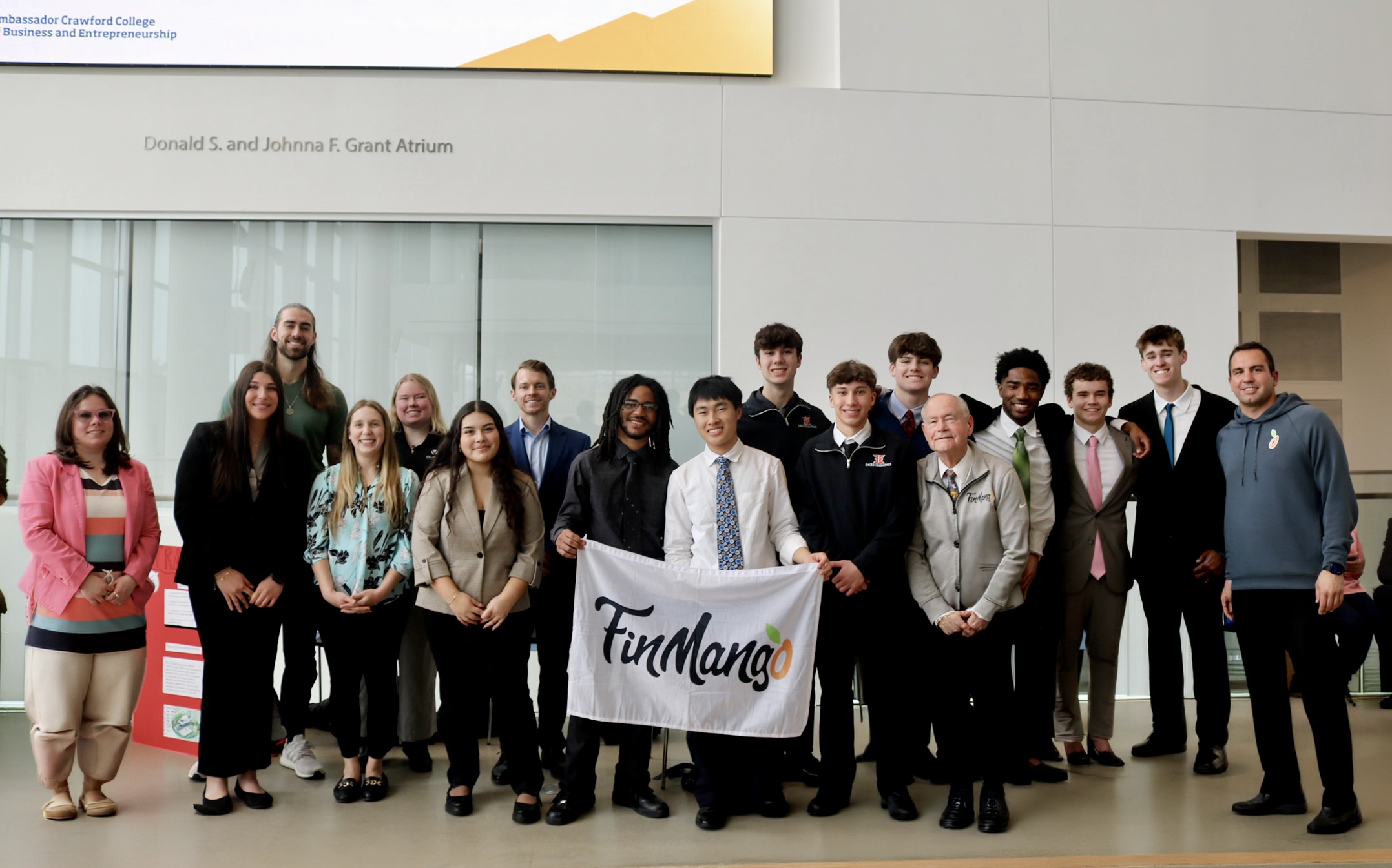 Students, mentors, and judges holding the FinMango flag at Barrier Breakers